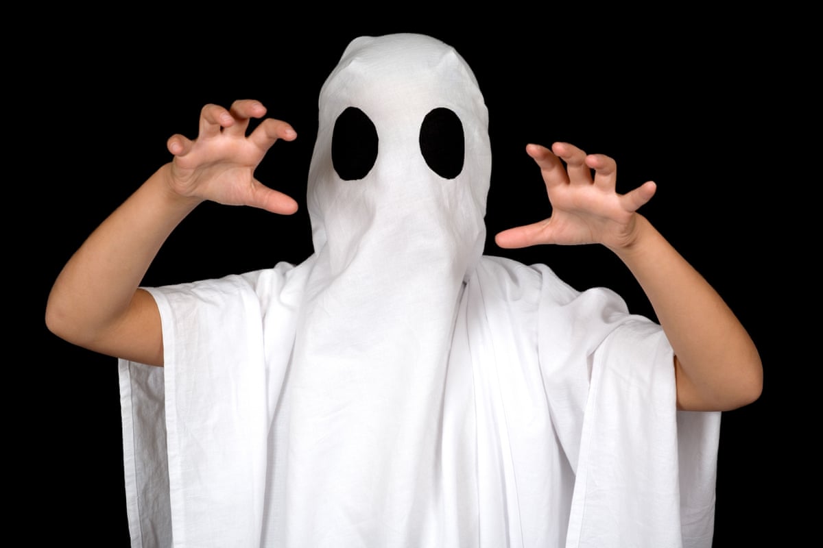 A child dressed as a ghost with a white sheet with black eyes