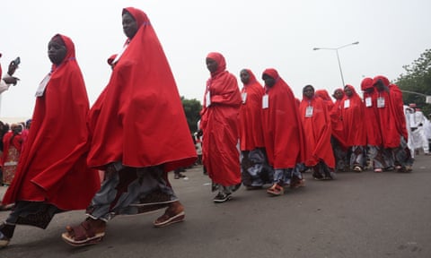 Une file de femmes portant des robes rouges.