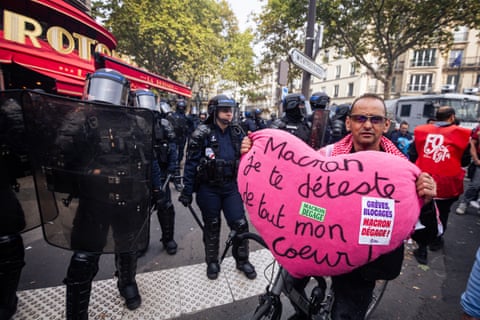 A man holds a stuffed pink heart that says: