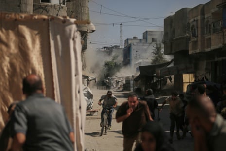 Palestinians run for cover during an Israeli military strike on a building in Gaza City, on Saturday.
