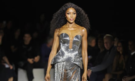 Naomi Cambell with long hair on a catwalk wearing a silver ensemble