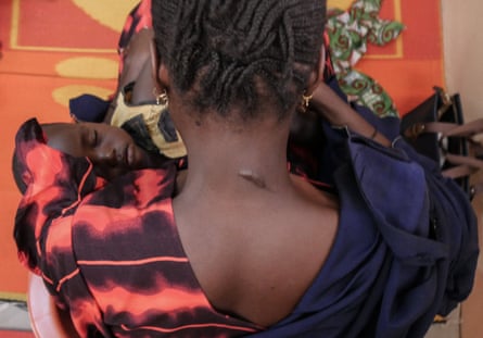 Menash holds her baby at the ‘safe space’. Her neck is scarred from when a Boko Haram militant tried to behead her