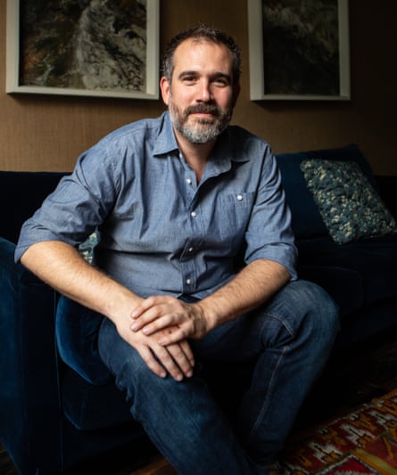 Dr Xand van Tulleken, bearded and in a blue shirt, sits on a sofa with hands clasped