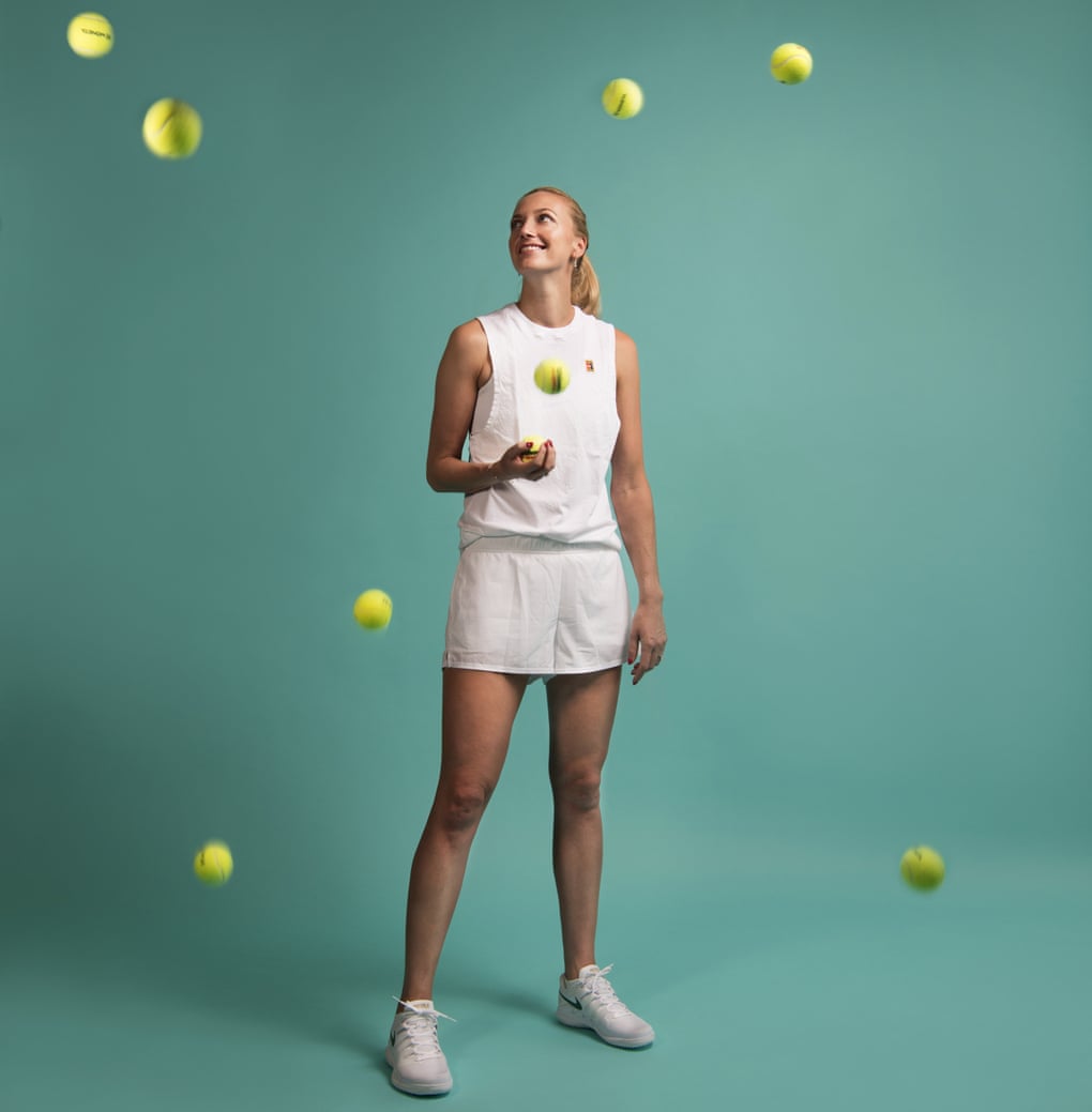 Tennis player Petra Kvitová against a turquoise background, looking up at tennis balls in the air around her. June 2019
