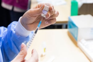 A nurse prepares a vaccine syringe.