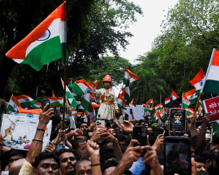 A massive crowd of protesters wave Indian national flags while marching through a tree-lined street during a demonstration led by the Cockroach Janta Party (CJP)