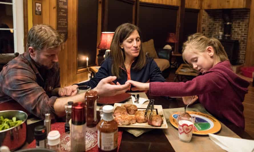 Chris Comstock and his wife, Kelly Chick Comstock, and daughter, Adelaide, pray before dinner.