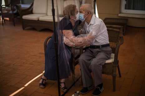 An elderly man and woman kiss and hug through a plastic screen because of Covid precautions at a nursing home in Spain, June 22 2020