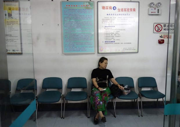 A woman sits in a Beijing hospital near posters showing how to avoid diabetes