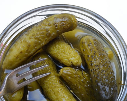 A fork rests among pickled gherkins packed inside a glass jar
