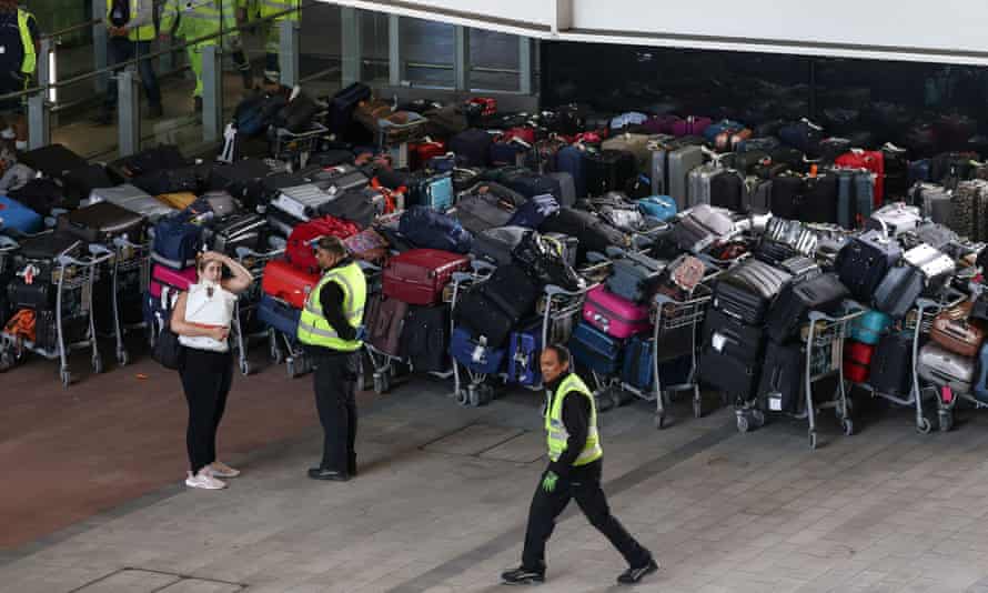 Airport workers stand next to lines of passenger luggage arranged outside Terminal 2 at Heathrow Airport yesterday