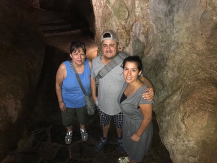 A man and two women smile as they pause by a rock formation.