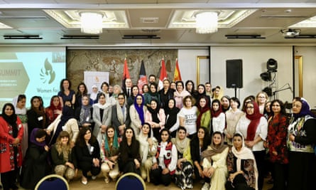 A group of women pose in a conference room in front of a row of flags.