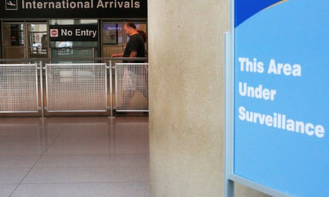 A sign warns of surveillance at the international arrival area, on the day that Donald Trump’s limited travel ban took effect.