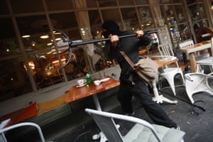A demonstrator throws a metal object at a restaurant window