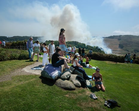 People watch as a wild fire climbs a hill near where thousands are set to gather for the total solar eclipse at El Monte De San Pedro park.