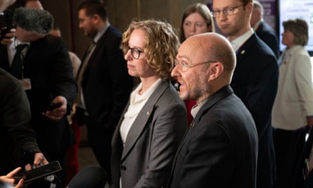 Lorna Slater and Patrick Harvie in a crowd of people, standing together talking to reporters who are off-camera