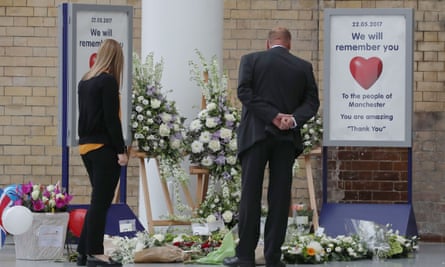 Commuters look at floral tributes placed at Manchester Victoria railway station, which reopened on Tuesday.