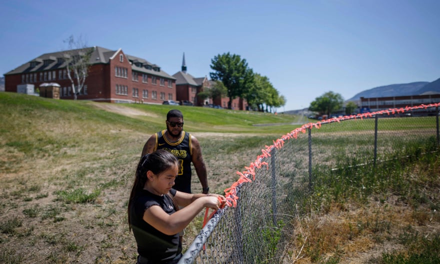 Autumn Peters places 215 ribbons on the fence behind the former Kamloops Indian residential school this week, in honor of the 215 children whose remains have been discovered buried near the facility, as well as her grandfather Clayton Peter, a survivor of the school, and all other survivors.