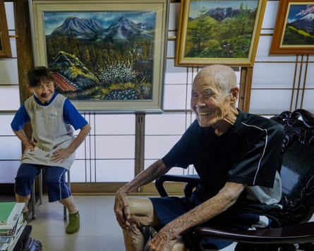 Kokichi and Yukiko sit in a room surrounded by large framed paintings