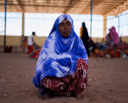 Aisha Ismail, a Yemeni refugee, at the Markazi humanitarian site in Obock, Djibouti, wearing a blue and white hijab and sitting in the sand