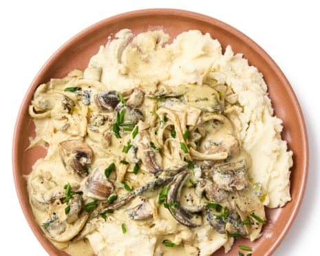 A plate of creamy mushroom stroganoff with chives, served beside mashed potato