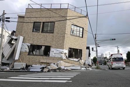 An ambulance passes by a collapsed building in Yatsushiro, Kumamoto prefecture, on Wednesday.