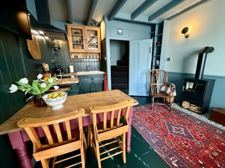 A blue-painted kitchen with beams, a rug and a wood burner