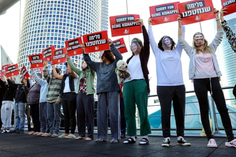 Protesters wearing masks depicting Israeli hostages hold signs reading "sorry for being kidnapped" in Tel Aviv.