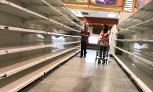 People walk past empty shelves at a supermarket in Caracas in January.