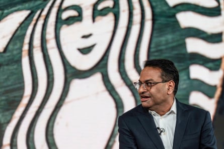 A man sits in front of a giant Starbucks logo