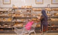 A customer in a headscarf, with a trolley and pink bag, shops for bread in the bakery aisle at a Sainsbury's supermarket in London
