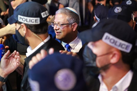 Itamar Ben Gvir smiles while surrounded by police officers at an election rally
