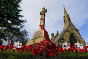 Great Ayton, UK. Knitted poppies arranged around the war memorial outside Christ church before Remembrance Day