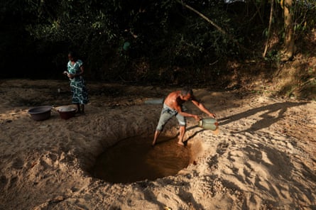 A villager digs a hole in a dried-out riverbed to collect water to take a bath in Ampara district, Sri Lanka.