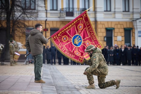 Volodymyr Zelenskiy handovers a flag to a serviceman in Kyiv.