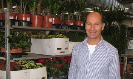 Maurits Philippo stands by a rack of shelves containing plants