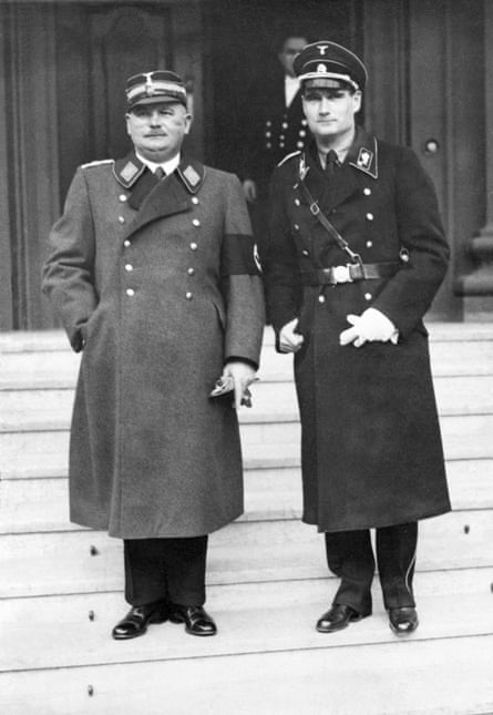two men in long coats stand