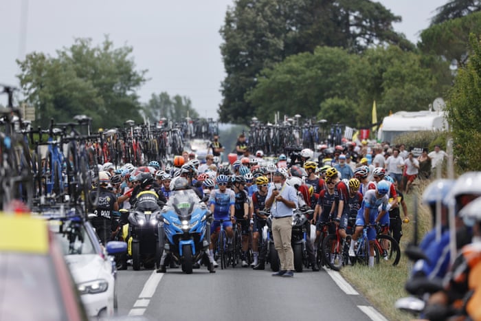 The peloton is stopped due to a protest further ahead on the road.