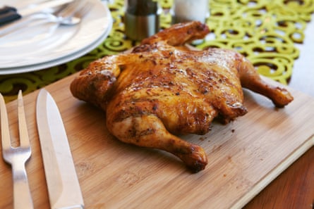 Whole cooked chicken with cutlery and spices.