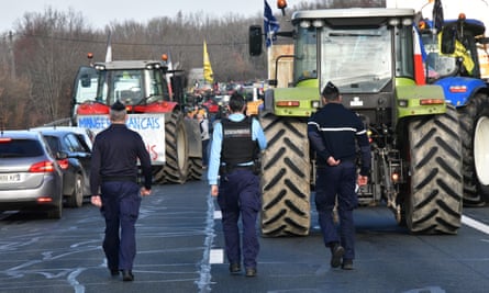 Police walk by tractors as farmers block the A20 highway near Argenton-sur-Creuse