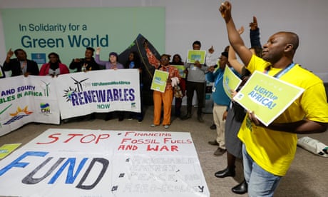 Activistas climáticos asisten a una acción conjunta en la Cop29 en Bakú, sosteniendo carteles que dicen "Ilumina África" y "Renovables ahora"