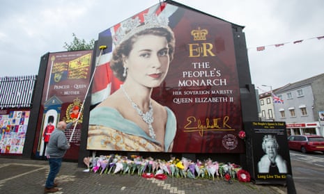 A worker cleans a mural of the Queen on Shankill Road in west Belfast