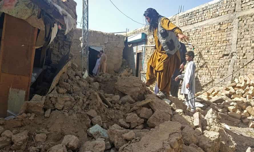 Residents gather next to the debris of their houses that collapsed following an earthquake in the remote mountainous district of Harnai