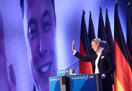 Weidel raising her hand at Musk, who is being broadcast on a huge video screen