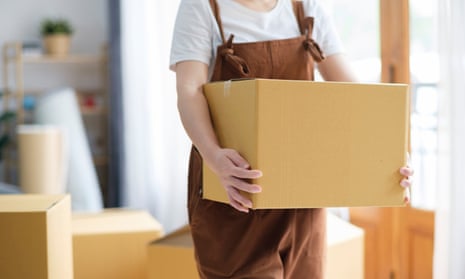 Woman in brown dungarees carrying a cardboard box