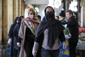 Women wearing protective face masks walk in a market in the Iranian capital Tehran on Sunday