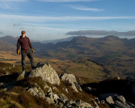Man standing on a rocky summit with mountains behind