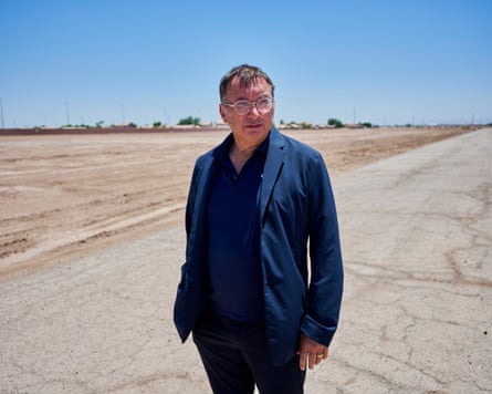 a man in a blue shirt stands on barren land
