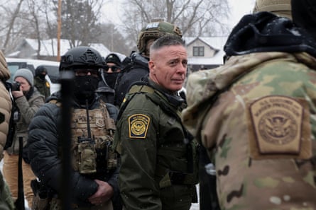 man in green uniform looks to side, surrounded by other officers standing outside